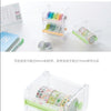 A clear plastic storage box filled with colorful decorative washi tape rolls and a cutter tool.