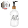 White refillable soap dispenser bottle with the word HANDS printed on it.