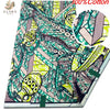 A close-up view of pink glitter African wax print fabric featuring intricate green and beige patterns.