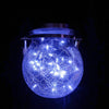 A blue crackle glass solar lantern glowing brightly against a dark background.