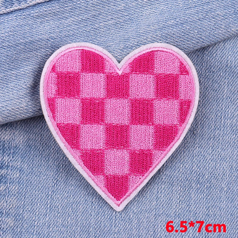 A pink checkered heart shaped iron-on patch sewn onto a light blue denim fabric.