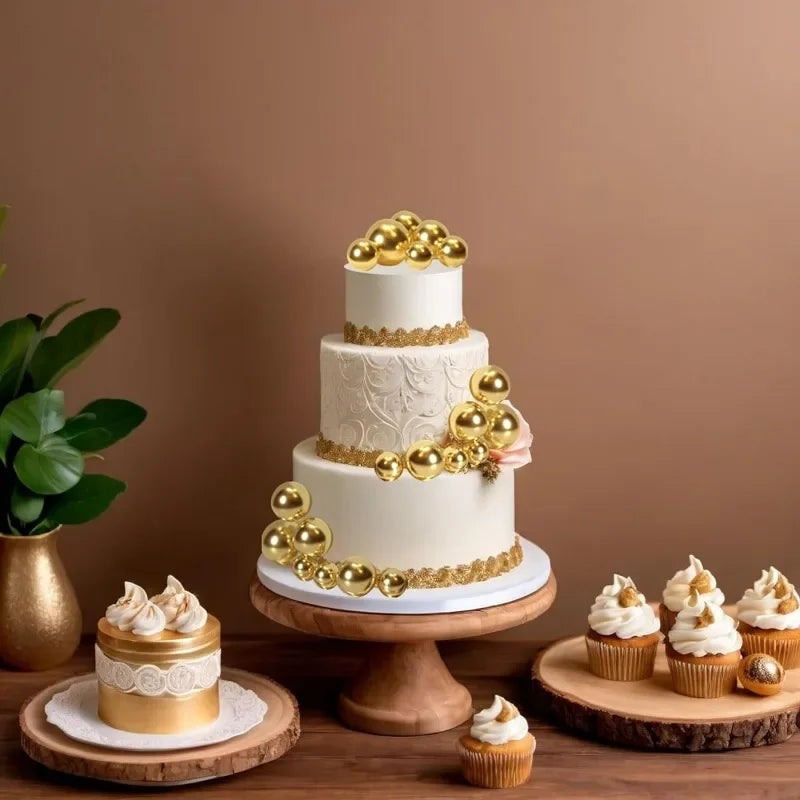 Mehrstöckiger weißer Kuchen mit goldenen Kugendekorationen und Goldrand auf Holzständer.