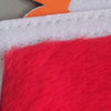 A close-up of a red felt board with white stitching and an orange cutout on a white background.