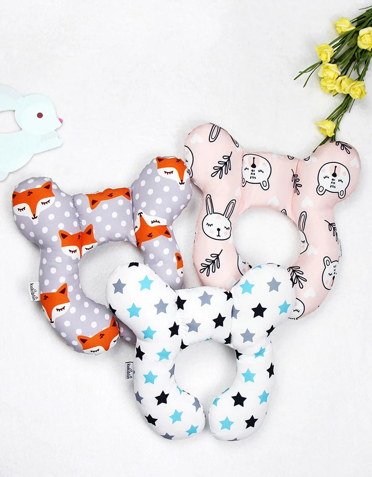 A set of soft, fabric baby head and neck support pillows featuring various animal faces in pink, gray, and white.