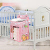A pink hanging diaper storage organizer with multiple compartments is shown inside a white crib.