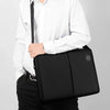 A man wearing a white shirt and dark pants is holding a black laptop briefcase.