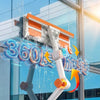 A white double-sided window cleaning tool with an orange squeegee and extension handle is shown cleaning a glass window.
