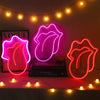 A neon sign shaped like lips glows pink on a dark background with string lights above.