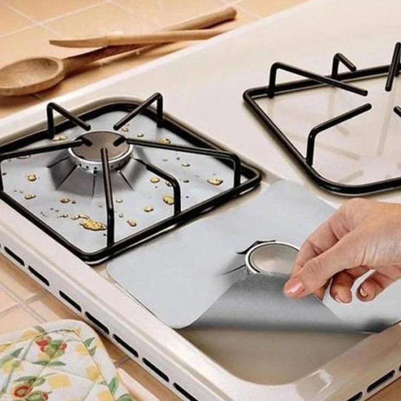 A hand places a reusable gas stove burner protector onto a stovetop grate.