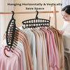 A display of multi-layer space-saving closet hangers hanging horizontally and vertically on a wooden rod.
