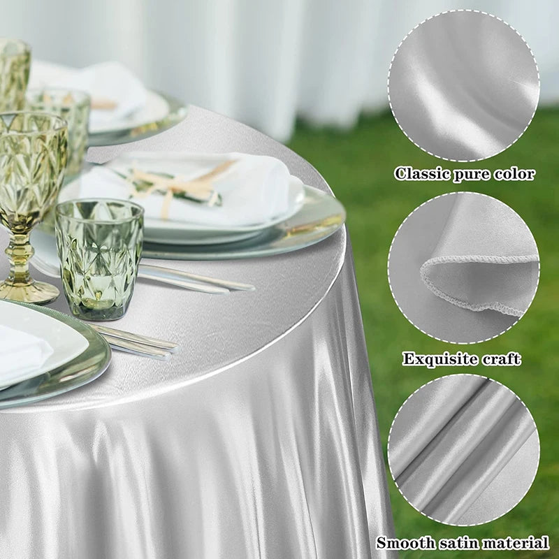 Elegant silver satin tablecloth draped on a round table with glassware and silverware.