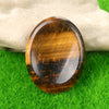 A polished, oval amber-colored natural crystal stone resting on green grass.