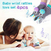 A woman is holding a baby while showing a set of four baby wrist rattles and teether socks
