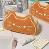 An orange caramel cat plush pencil case with a light beige lining is shown on a white surface.
