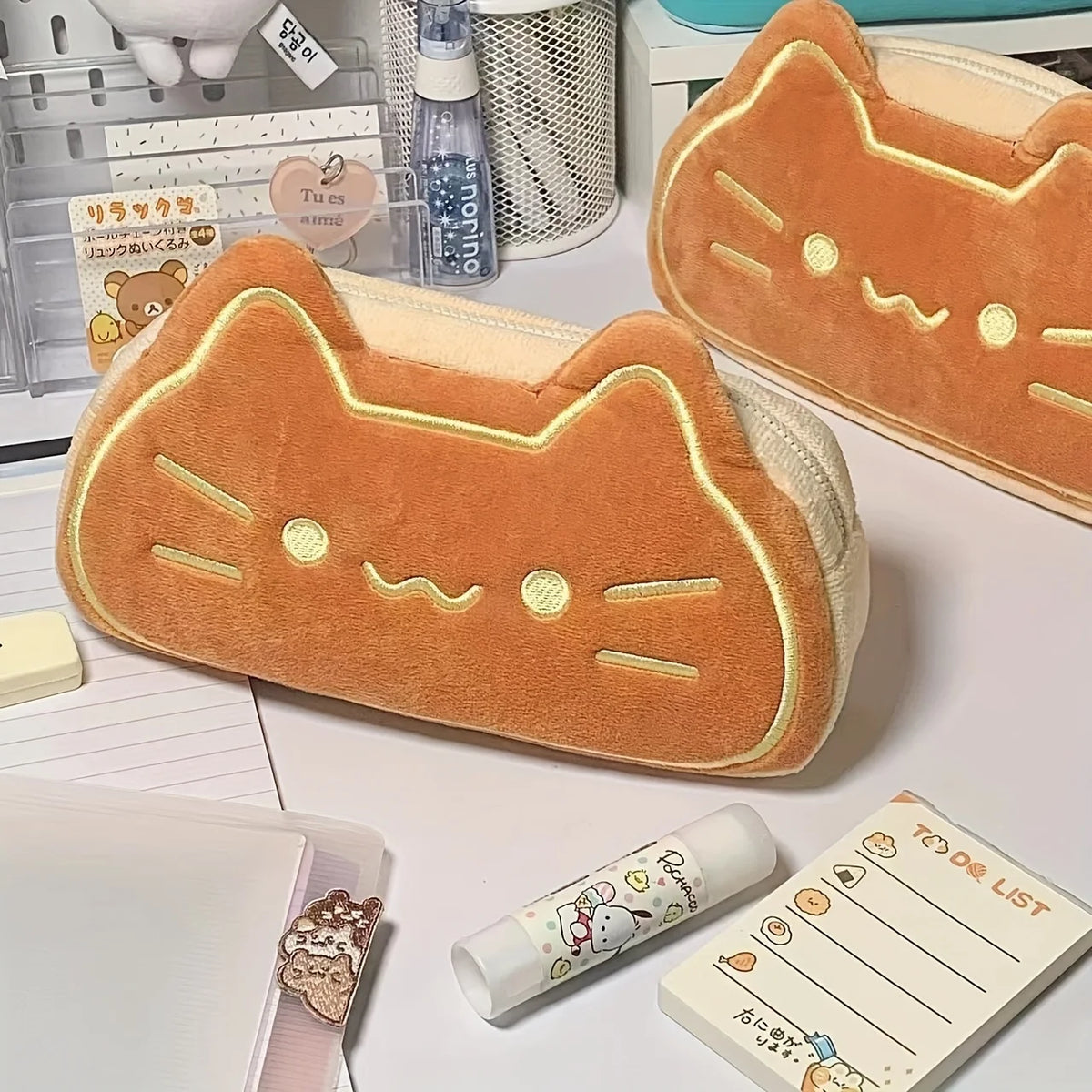 An orange caramel cat plush pencil case with a light beige lining is shown on a white surface.
