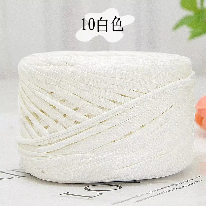 A ball of white metallic flat ribbon yarn for crochet and knitting displayed on a surface.