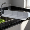 A white flexible silicone sink splash guard is installed in a black granite kitchen sink.