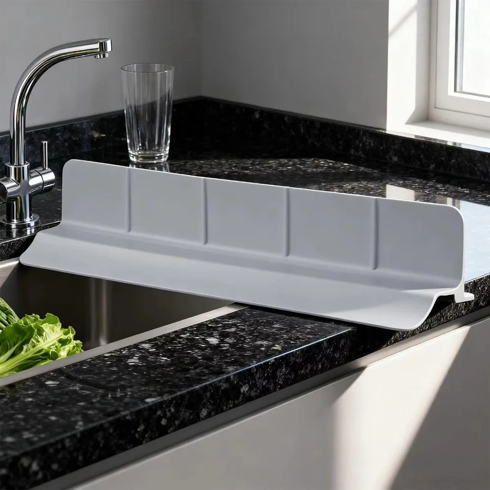 A white flexible silicone sink splash guard is installed in a black granite kitchen sink.