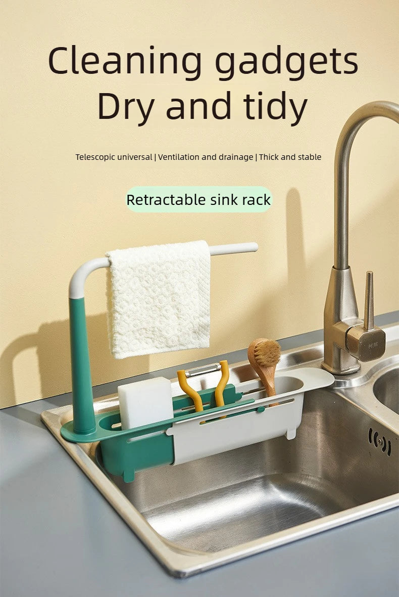 A white and green retractable sink rack holds a wet towel and sponge in a stainless steel kitchen sink.