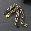 A close-up of a chunky stainless steel Cuban chain bracelet featuring black and gold links.