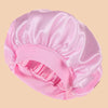 A pink satin wide brim shower cap is shown from above, highlighting its silky texture and gathered design.