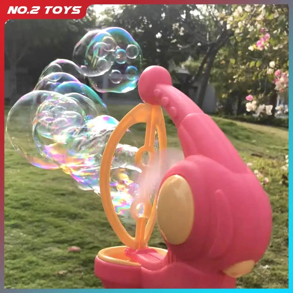 A pink automatic bubble gun is shown in a close-up, shooting iridescent bubbles outdoors.