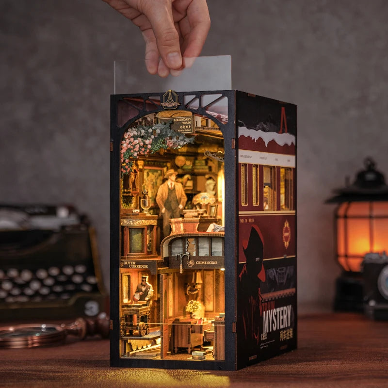 A dark wooden box containing a detailed diorama of an old bookstore with shelves and books, illuminated by LED lighting.