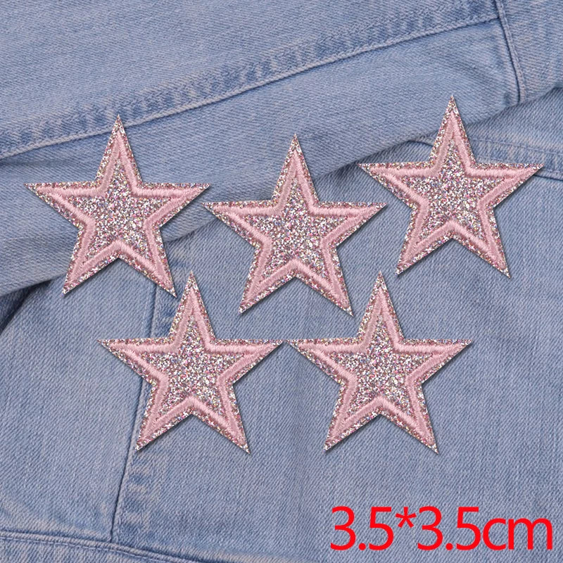 Set of five pink glitter star iron-on embroidered patches on a denim fabric.