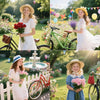A young girl in a white dress holds a bouquet of pink flowers while standing next to a bicycle in a garden setting.