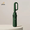 A dark green fully automatic windproof folding umbrella standing upright on a white surface.