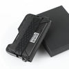 A black minimalist leather card holder with a bottle opener resting on a dark box.