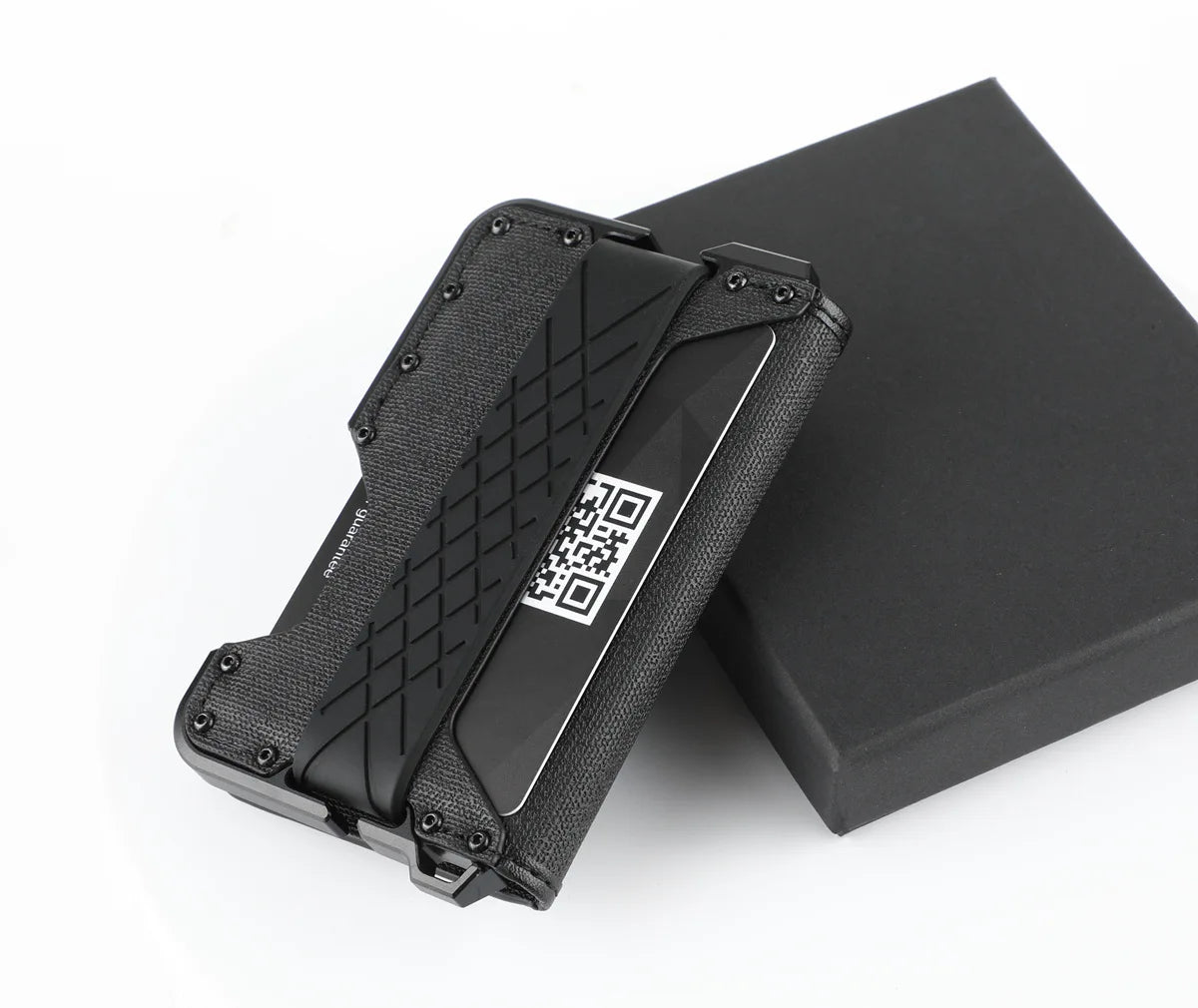 A black minimalist leather card holder with a bottle opener resting on a dark box.