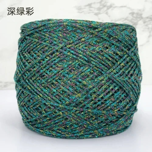 A ball of metallic silk crochet yarn with a teal and silver shimmer texture for knitting and macrame.