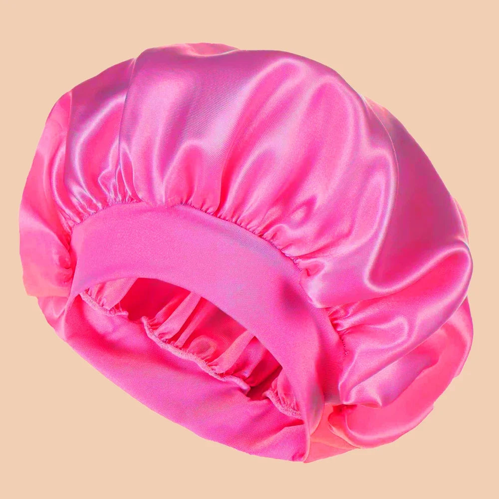 A bright pink satin wide brim shower cap folded and displayed against a light background.