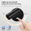 A hand touches a black magnetic rechargeable light switch to adjust the brightness of a lamp.