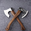 A pair of hand-forged Viking tomahawk axes with wooden handles and metal blades resting on a gray surface.