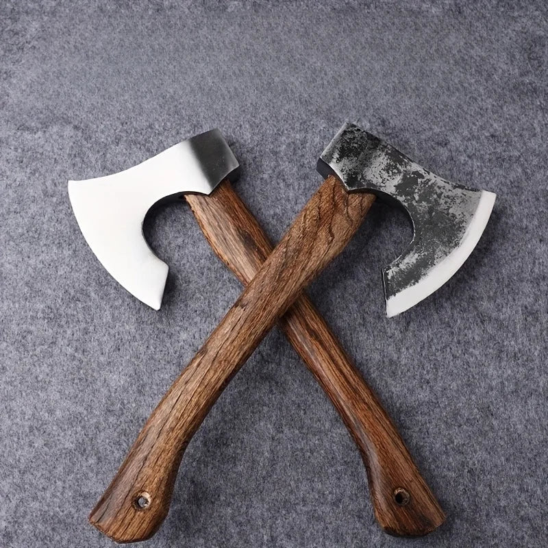 A pair of hand-forged Viking tomahawk axes with wooden handles and metal blades resting on a gray surface.