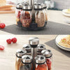 A set of rotating glass spice jars with a rack, featuring various ground spices and herbs.