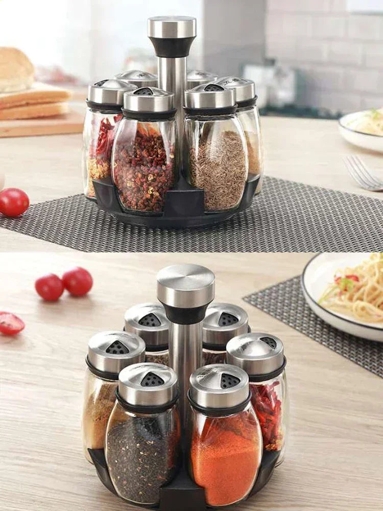 A set of rotating glass spice jars with a rack, featuring various ground spices and herbs.