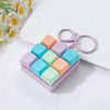 A purple box filled with colorful silicone clicking keyboard fidget toys and a purple keychain.