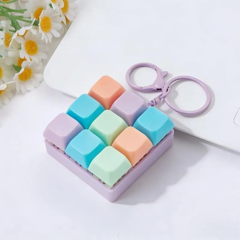 A purple box filled with colorful silicone clicking keyboard fidget toys and a purple keychain.