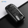 A black carbon fiber car key cover for VW and Skoda models shown on a dark surface.