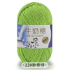 A ball of light green milk cotton blend yarn with a white label featuring Chinese text and an illustration of a cow.