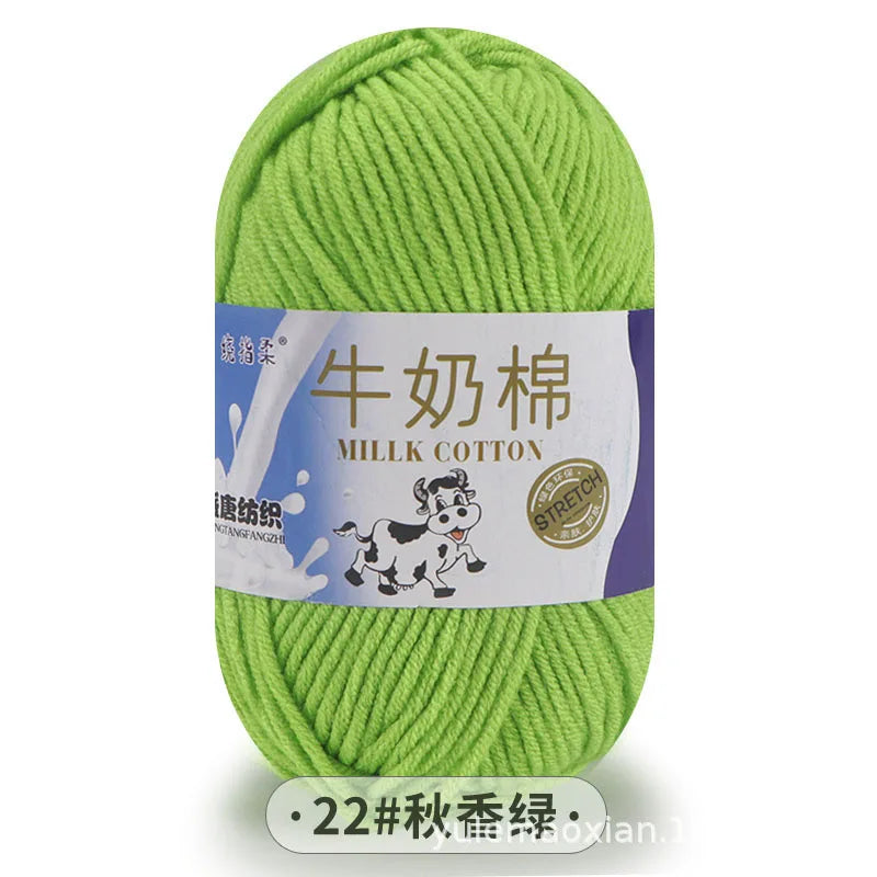 A ball of light green milk cotton blend yarn with a white label featuring Chinese text and an illustration of a cow.