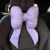 A lavender butterfly bow tie neck pillow with a textured cotton and linen cover is shown in a car seat interior.