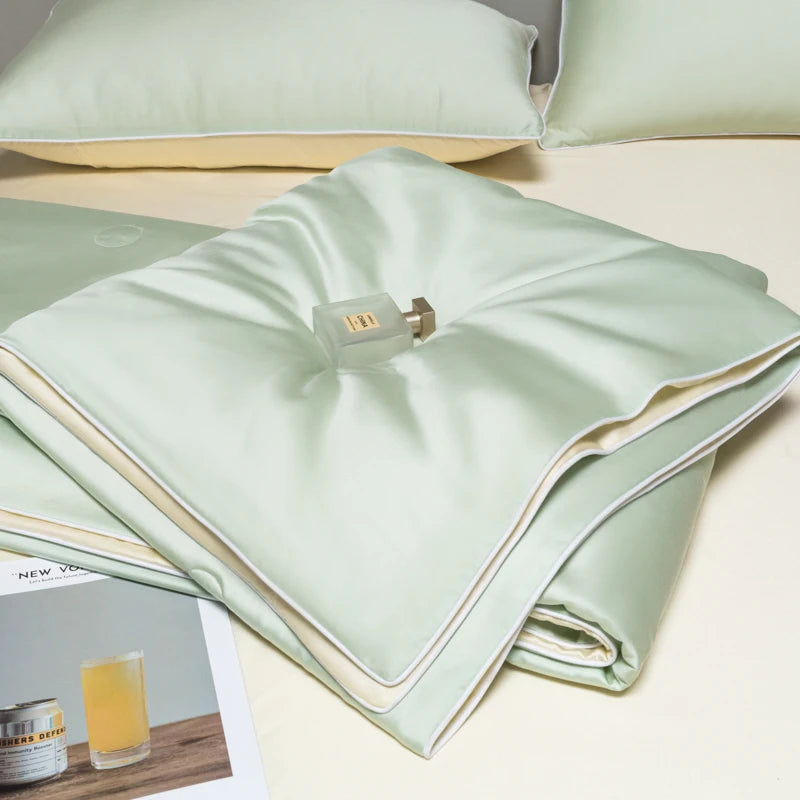 Light mint green ice silk quilt folded neatly on a white surface with a small metal tag.