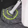 A gray self-wringing spin mop with a white handle and green accents is shown on a dark surface.