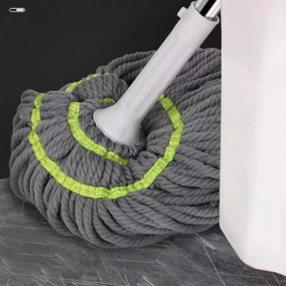 A gray self-wringing spin mop with a white handle and green accents is shown on a dark surface.