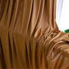 Close-up of flowing, rich brown or bronze stretch jersey fabric draped in soft folds.