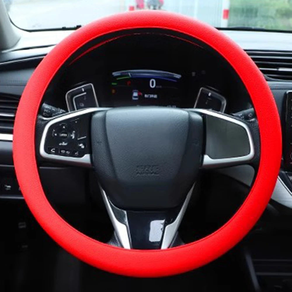 A red silicone steering wheel cover is shown inside a car, featuring a black steering wheel and controls.